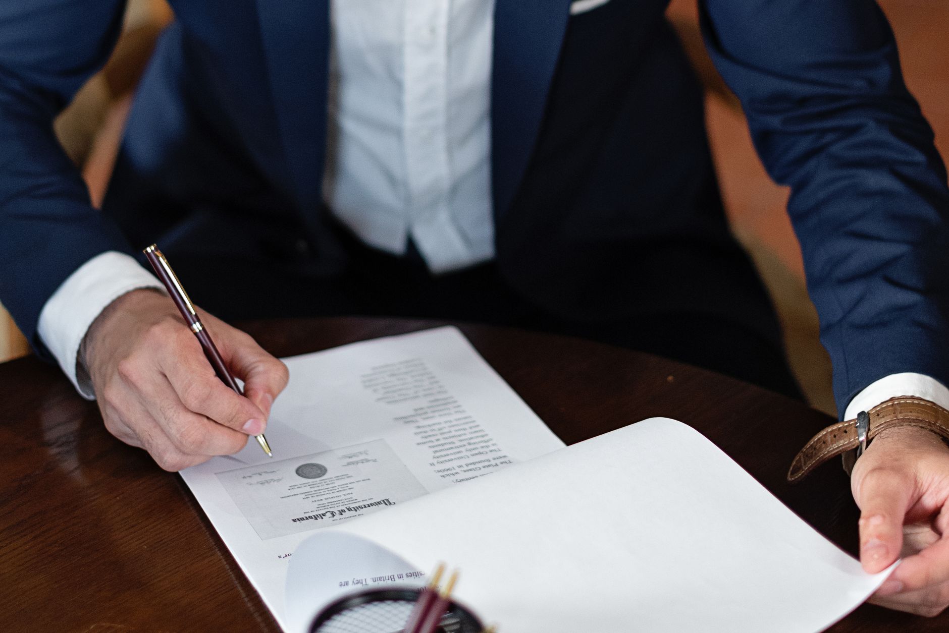 Person in a suit signing a business document
