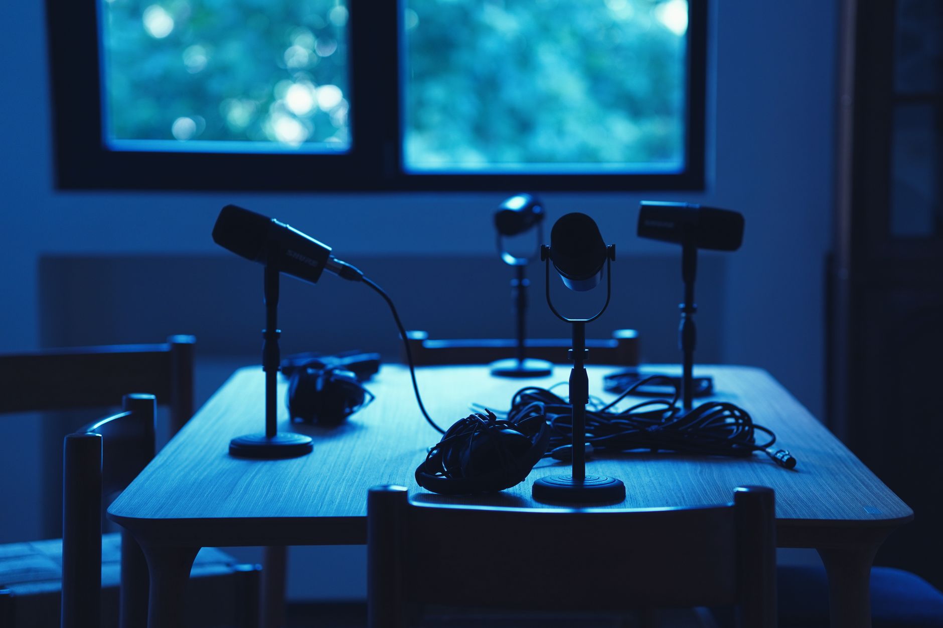 Empty podcast table with microphones in a blue-lit studio